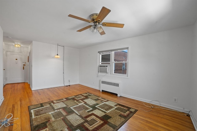 unfurnished room with baseboards, wood finished floors, and radiator