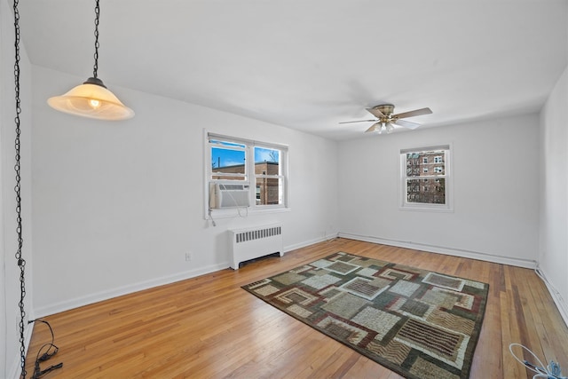 interior space featuring radiator heating unit, wood-type flooring, cooling unit, and baseboards