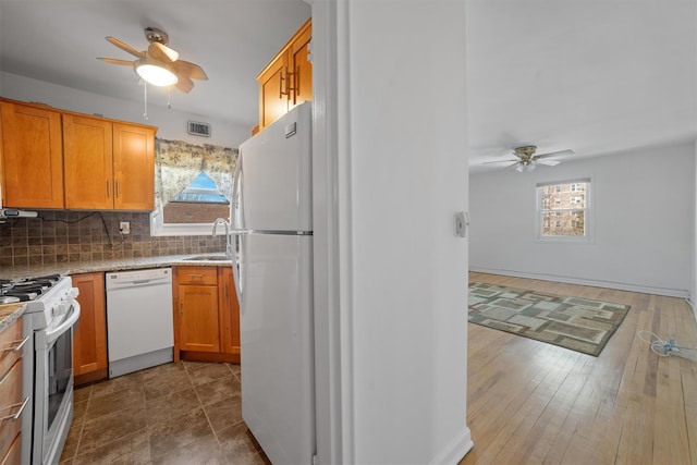 kitchen featuring white appliances, a sink, a ceiling fan, visible vents, and tasteful backsplash