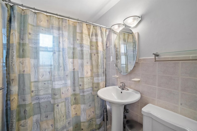 bathroom featuring a shower with curtain, a sink, toilet, and tile walls