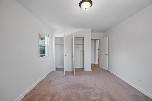 unfurnished bedroom featuring multiple closets, light carpet, and baseboards