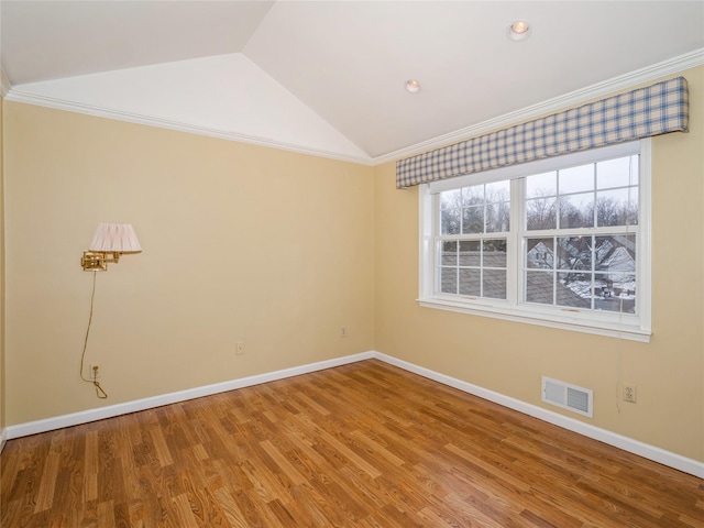 spare room with crown molding, lofted ceiling, and hardwood / wood-style floors