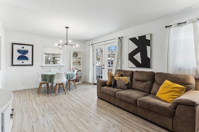 living room featuring a chandelier, french doors, baseboards, and light wood-style floors