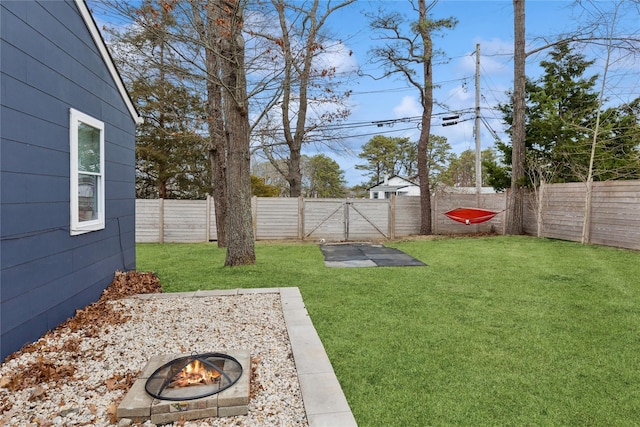 view of yard with a gate, a fenced backyard, and an outdoor fire pit