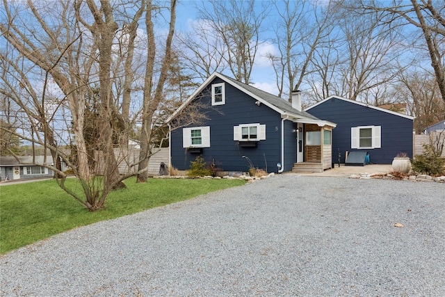 bungalow-style house with a front lawn, a chimney, and driveway