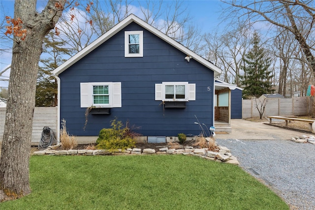 view of side of property with a lawn, driveway, and fence