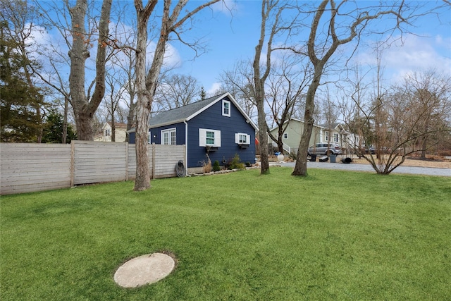 view of side of home featuring a wall unit AC, a lawn, and fence