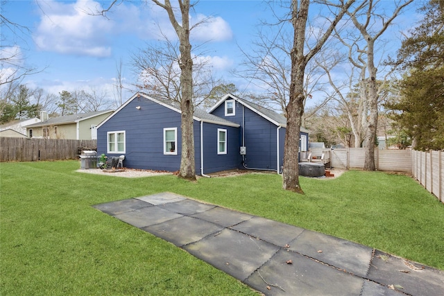 rear view of property featuring a lawn and a fenced backyard