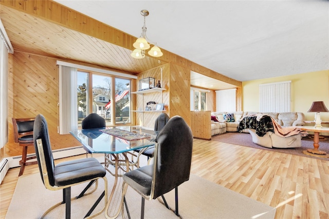 dining area featuring a notable chandelier, wooden walls, and light hardwood / wood-style flooring