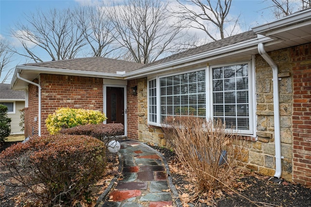 property entrance featuring stone siding, brick siding, and roof with shingles