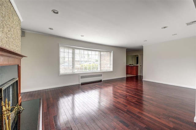 unfurnished living room with a fireplace, visible vents, radiator heating unit, wood-type flooring, and crown molding