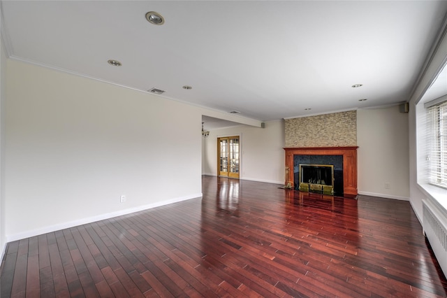 unfurnished living room featuring baseboards, a fireplace with flush hearth, visible vents, and hardwood / wood-style floors