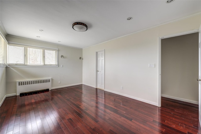 spare room featuring radiator heating unit, wood-type flooring, and baseboards