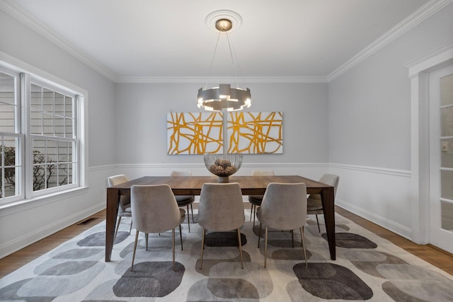 dining space featuring hardwood / wood-style flooring, crown molding, and a notable chandelier