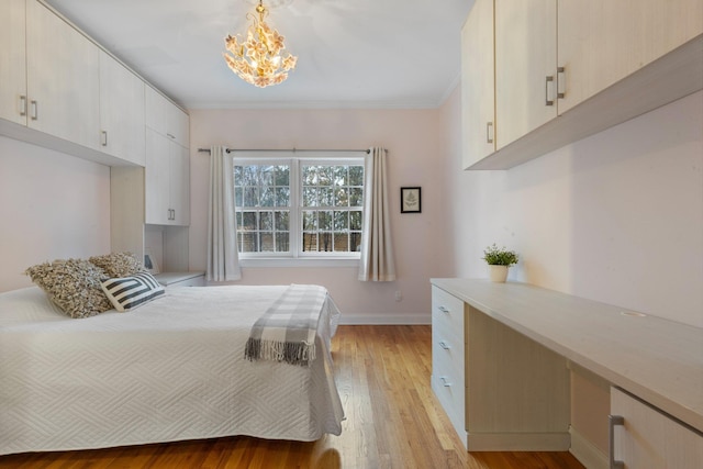 bedroom featuring crown molding, built in desk, an inviting chandelier, and light hardwood / wood-style flooring