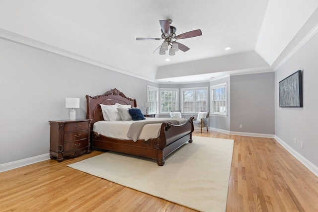 bedroom featuring crown molding, a tray ceiling, light hardwood / wood-style flooring, and ceiling fan