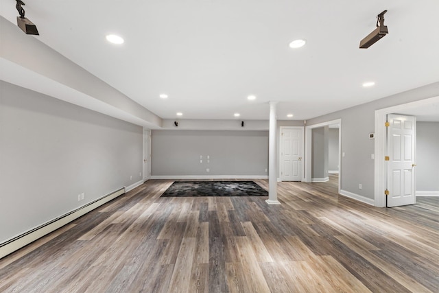 unfurnished living room with baseboard heating and wood-type flooring