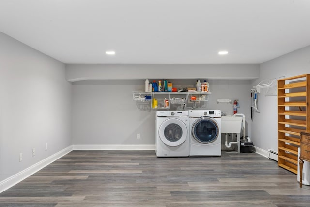 laundry room featuring dark wood-type flooring, independent washer and dryer, a baseboard radiator, and sink