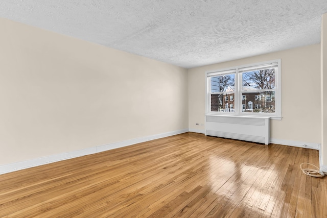 unfurnished room with radiator, light hardwood / wood-style flooring, and a textured ceiling