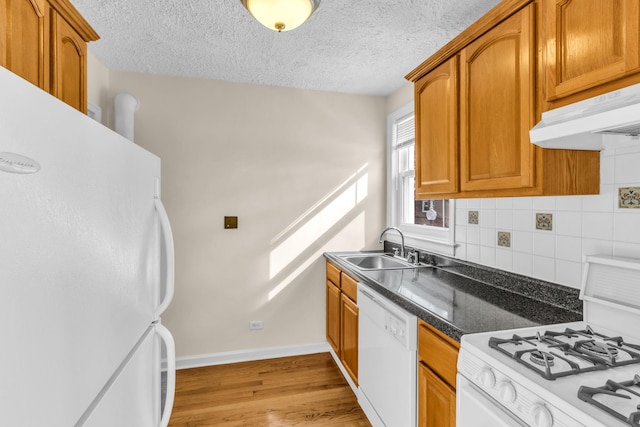 kitchen with sink, white appliances, light hardwood / wood-style floors, a textured ceiling, and decorative backsplash