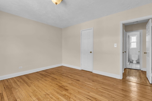 unfurnished room with light hardwood / wood-style flooring and a textured ceiling