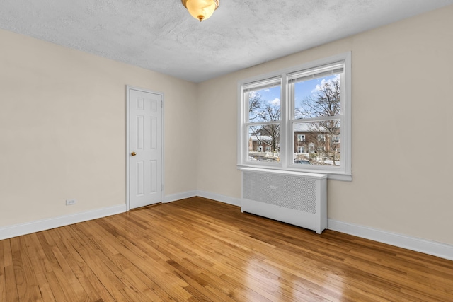 unfurnished room featuring radiator heating unit, a textured ceiling, and light wood-type flooring