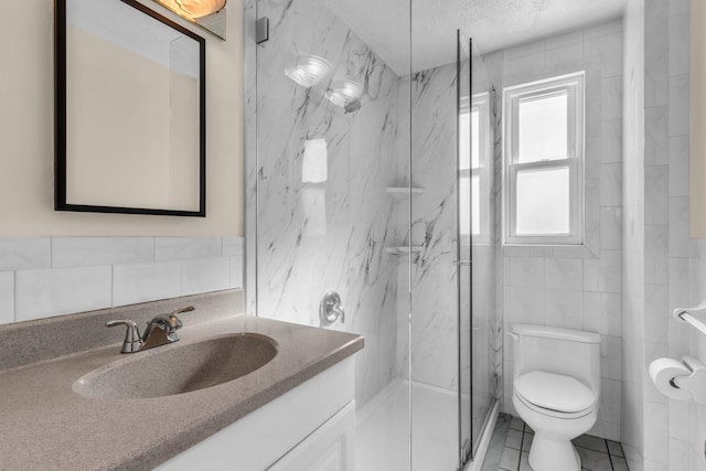 bathroom with tile walls, vanity, a textured ceiling, toilet, and walk in shower