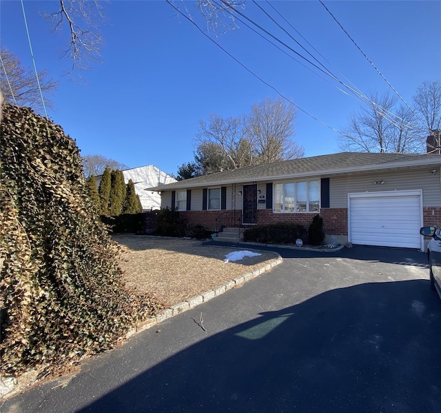 view of front of home with aphalt driveway, brick siding, a chimney, and an attached garage