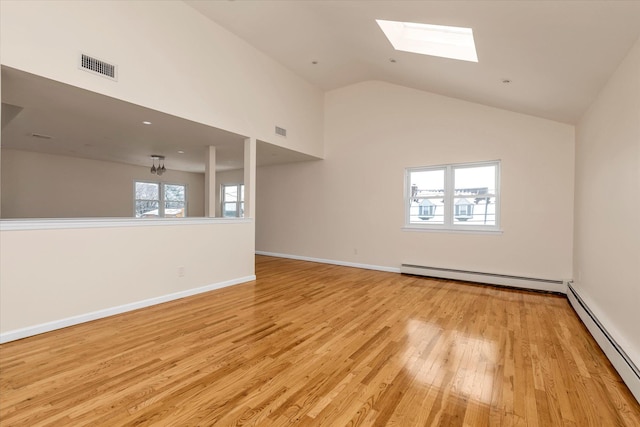 empty room featuring a baseboard heating unit, a skylight, high vaulted ceiling, and light wood-type flooring