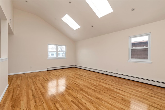 empty room featuring a skylight, light hardwood / wood-style flooring, and high vaulted ceiling