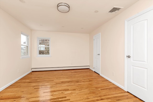 unfurnished room featuring a baseboard radiator and light hardwood / wood-style floors