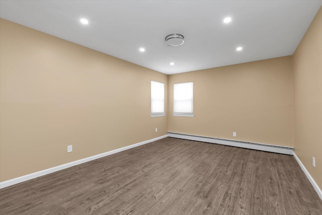 unfurnished room featuring a baseboard heating unit and wood-type flooring