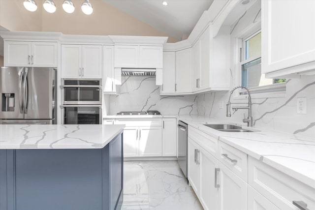 kitchen featuring decorative backsplash, lofted ceiling, white cabinetry, a sink, and stainless steel appliances