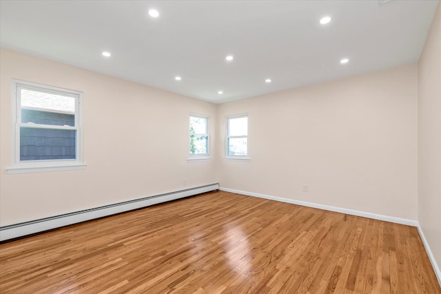 empty room featuring light wood-style floors, baseboards, a baseboard heating unit, and recessed lighting