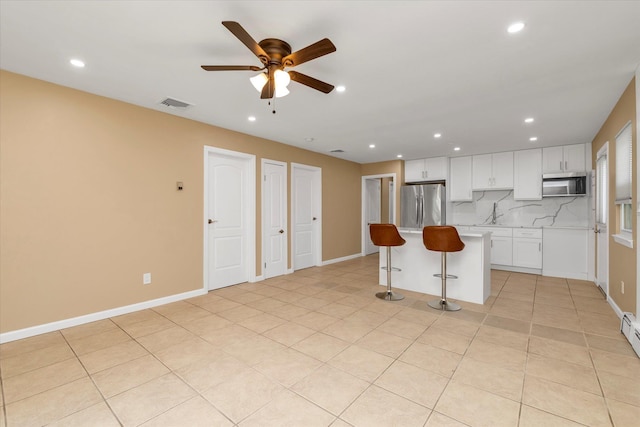 kitchen featuring visible vents, a kitchen island, ceiling fan, a kitchen bar, and appliances with stainless steel finishes