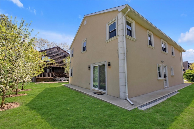 back of house with a lawn and stucco siding