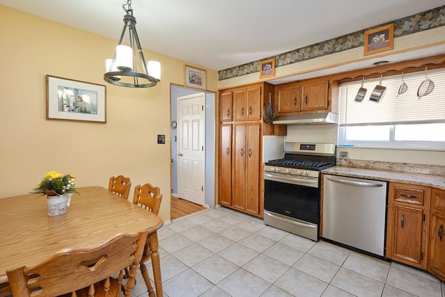 kitchen featuring stainless steel appliances, light tile patterned floors, and decorative light fixtures