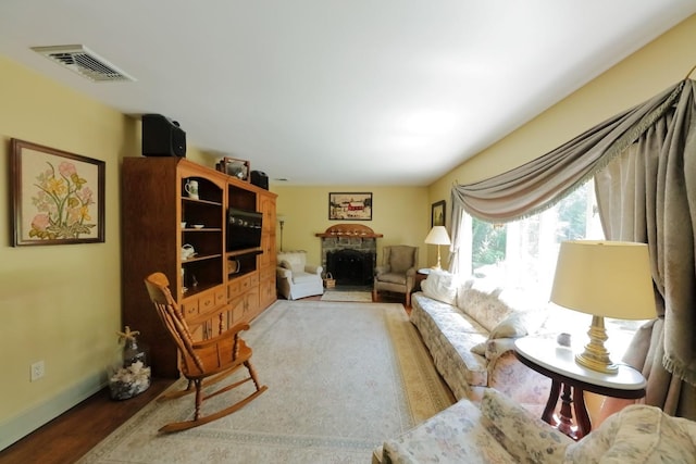 living room with a fireplace, wood finished floors, visible vents, and baseboards