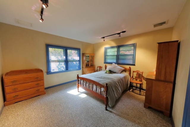 carpeted bedroom with visible vents and track lighting