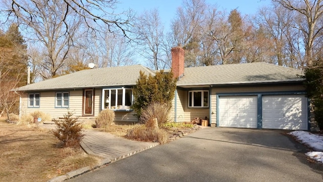 single story home with roof with shingles, driveway, a chimney, and an attached garage