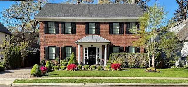 view of front facade with driveway, a front lawn, and brick siding