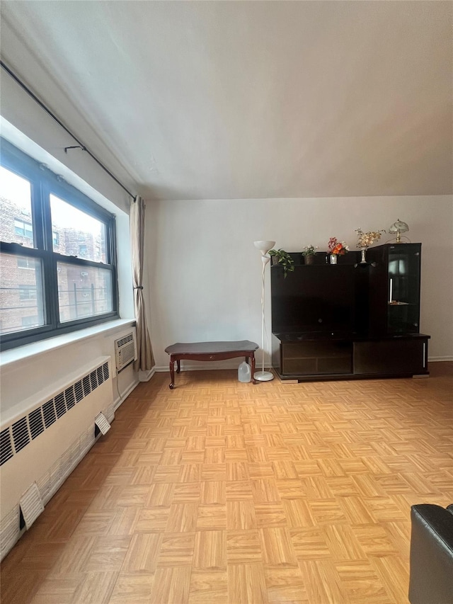 sitting room featuring radiator, a wall unit AC, and light parquet floors