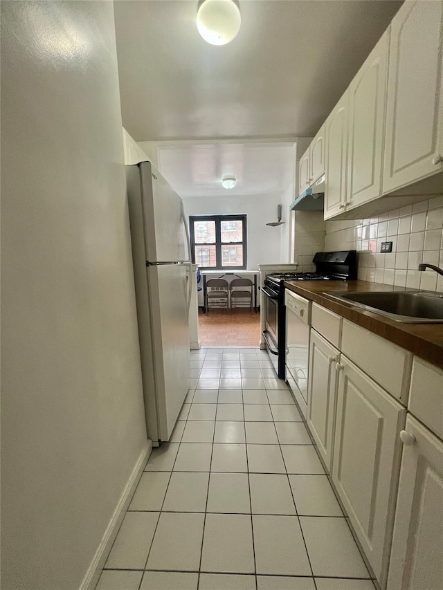 kitchen with sink, tasteful backsplash, light tile patterned floors, white appliances, and white cabinets