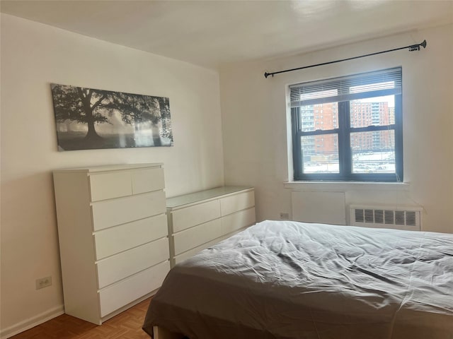 bedroom with light parquet flooring and radiator heating unit