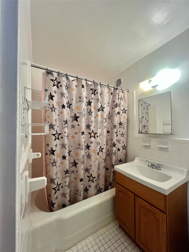 bathroom featuring tile patterned flooring, shower / tub combo, tile walls, vanity, and decorative backsplash