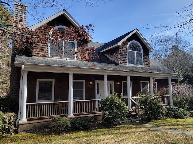 view of front of home with roof with shingles, a porch, and a front yard