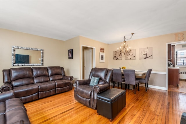 living room featuring an inviting chandelier, radiator heating unit, and light hardwood / wood-style floors