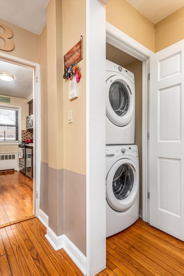 laundry area featuring radiator, hardwood / wood-style floors, and stacked washer / dryer