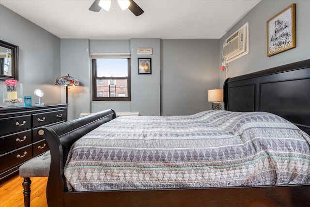 bedroom with hardwood / wood-style flooring, ceiling fan, and a wall unit AC