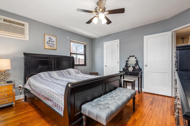 bedroom featuring ceiling fan, hardwood / wood-style floors, and a wall unit AC